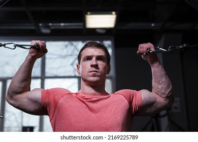 Close up of a determined bodybuilder doing bicep curls in cable crossover gym machine - Powered by Shutterstock