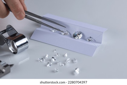 Close up of diamonds of different cuts and sizes on light background with shadows.