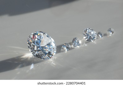 Close up of diamonds of different cuts and sizes on light background with shadows. - Shutterstock ID 2280704401
