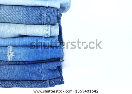 Close up at different blue jeans Stack isolated on white background.Pile of denim blue jean of fashion design use for creative.Fashion,canvas or designing concept.Have copy space.