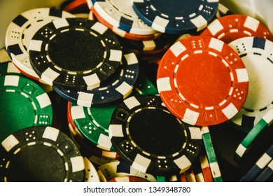 Close Up Of Different Color Casino Poker Chips Background. Many Old Poker Chips. Game Gambling And Entertainment Concept. Subject Is Blurry When Viewed At Full Resolution.