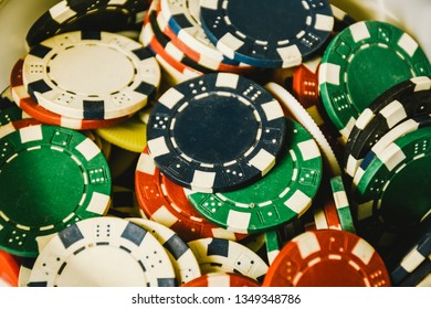 Close Up Of Different Color Casino Poker Chips Background. Many Old Poker Chips. Game Gambling And Entertainment Concept. Subject Is Blurry When Viewed At Full Resolution.