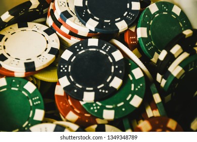 Close Up Of Different Color Casino Poker Chips Background. Many Old Poker Chips. Game Gambling And Entertainment Concept. Subject Is Blurry When Viewed At Full Resolution.