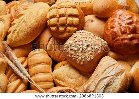Close up of different types of breads and golden buns with ears of wheat. Food and bakery concept. Salty and sweet food. Bakery and carbohydrates.