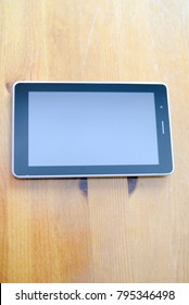 Close up of digital tablet pc mockup touch screen device laying on wooden desk. Modern wireless internet electronic gadget flat lay topview copyspace. Work, watching video, game fun, texting design