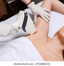 Close up of diode laser applicator on female armpit. Macro shot of laser hair removal head touching woman skin with protective gel during session.