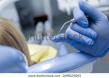 Close up of a diode laser tip in a gloved hand beside a child patient, showing pediatric laser dentistry and sterile care.