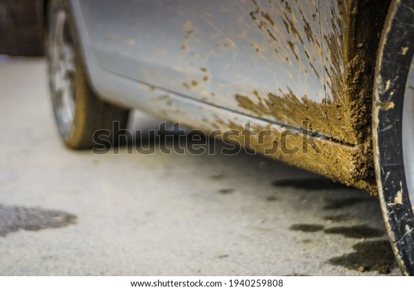 Close up of dirty car wheel with rubber tire\
covered with yellow\
mud.\

