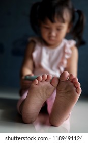 Close Up Of Dirty Feet Of A Little Asian Girl While Watching Phone.