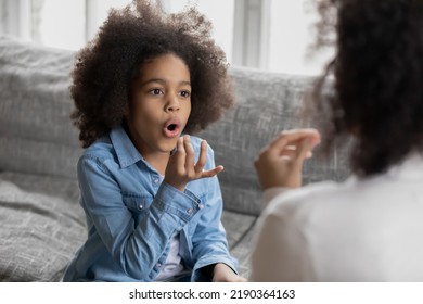 Close up disabled African American girl practicing sign language with mother or teacher, showing symbols, using gestures, interacting, repeating sounds, involved in speaking lesson at home - Shutterstock ID 2190364163