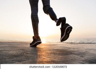 Close up of disabled woman with prosthetic leg running outdoor at the beach - Powered by Shutterstock