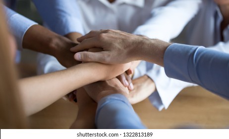 Close up diverse business people putting hands together, showing support and unity, multiracial colleagues involved in team building activity, staff training concept, start working together, teamwork - Shutterstock ID 1322813189