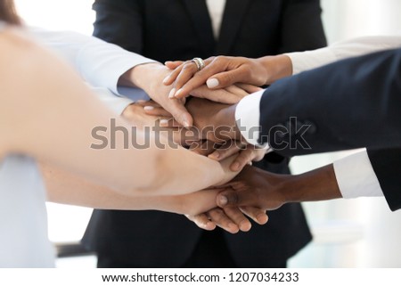 Close up of diverse employees stack hands in pile show mutual support, multiethnic workers promise loyalty and help involved in team building activity, team united at motivational business training