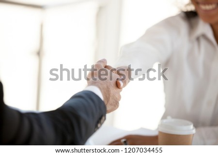 Close up of diverse happy workers shake hands greeting at business meeting in office, colleagues handshake getting acquainted at briefing, partners introduce making good first impression