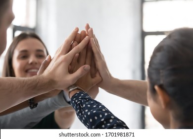 Close up of diverse motivated colleagues give high five celebrate shared victory or win at briefing, multiethnic businesspeople engaged in teambuilding activity at office meeting, reward concept - Shutterstock ID 1701981871