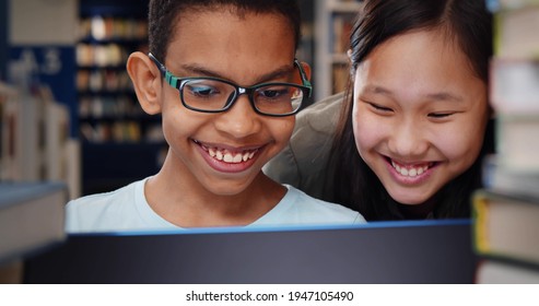 Close up of diverse school students studying and reading together in library. Portrait of asian preteen girl helping african boy with homework on laptop in school library - Powered by Shutterstock