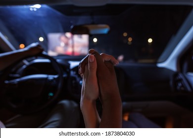 Close up of diverse young couple holding their hands together while having a romantic evening. Young people watching a movie at drive in cinema from the front seats of the car. Entertainment concept - Powered by Shutterstock