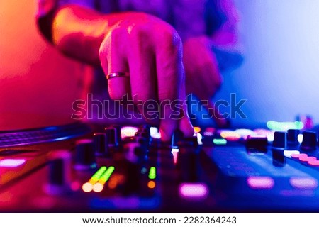 Close up of DJ hands on dj console mixer during concert in the club
