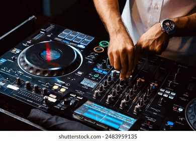 Close up DJ plays live set and mixing music on turntable console in the night club. Disc Jokey Hands on a sound mixer station at club party. DJ mixer controller panel for playing music and partying.