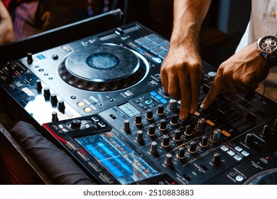 Close up DJ plays live set and mixing music on turntable console in the night club. Disc Jokey Hands on a sound mixer station at club party. DJ mixer controller panel for playing music and partying.