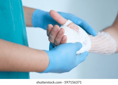 close up of doctor bandaging one hand after an accident - Shutterstock ID 597156371