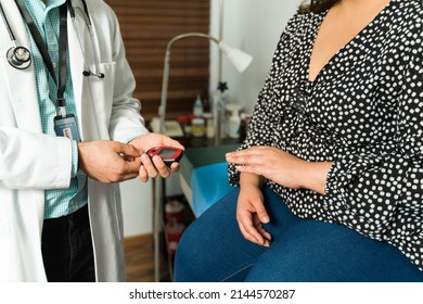 Close Up Of A Doctor Checking The Blood Glucose With A Monitor. Young Woman With Diabetes And Obesity At A Medical Check-up