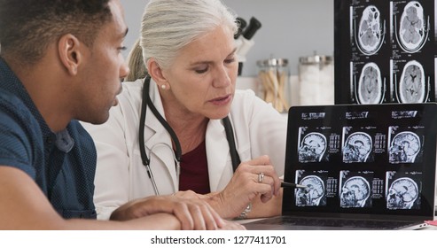 Close Up Of Doctor Consulting With Patient On His Concussion Looking At Ct Scans