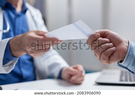 Close up of doctor giving prescription paper to patient at checkup appointment. Physician handing out document for treatment and medicine against disease. People meeting at consultation