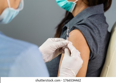close up doctor in gloves holding syringe and making injection to patient in medical mask. Covid-19 or coronavirus vaccine - Shutterstock ID 1766534462