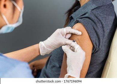 close up doctor in gloves holding syringe and making injection to patient in medical mask. Covid-19 or coronavirus vaccine - Shutterstock ID 1767196094