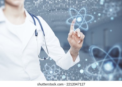 Close Up Of Doctor Hand Pointing At Abstract Glowing Atom Hologram On Blurry Hospital Or Clinic Interior Background. Nuclear Medicine, Energy And Medical Research Concept