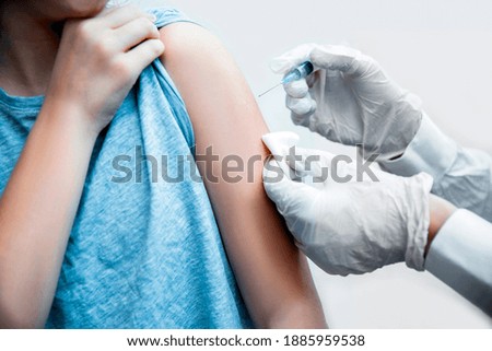 Close up of a Doctor hand with syringe vaccinating the shoulder of young patient. Flu Vaccination Injection on Arm protect from Covid-19. Vaccine disease preparing for human clinical vaccination shot