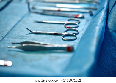 Close up of doctor hands during surgery in operation room. Sterile surgery instruments used in a real operation. Focus is on the row of clamp handles.