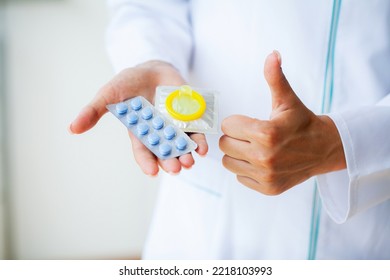 Close up doctor holding pill and condom for men health