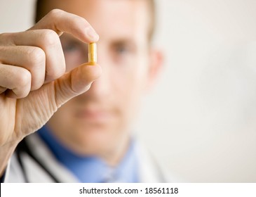 Close Up Of Doctor Holding Small Yellow Pill