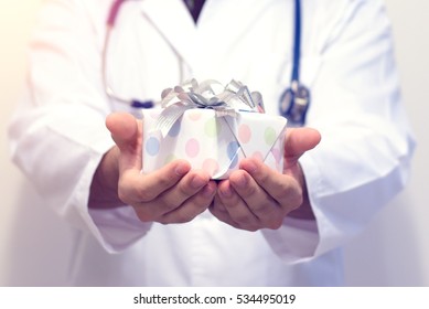 Close Up Of Doctor Holding White Gift With Blue Tone