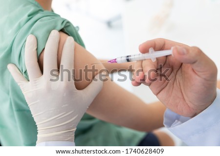 Close up of a Doctor making a vaccination in the shoulder of patient, Flu Vaccination Injection on Arm, coronavirus, covid-19 vaccine disease preparing for human clinical trials vaccination shot.