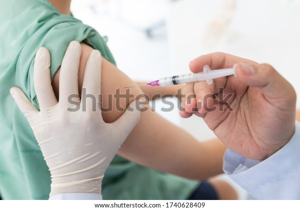 Close up of a Doctor making a vaccination in the\
shoulder of patient, Flu Vaccination Injection on Arm, coronavirus,\
covid-19 vaccine disease preparing for human clinical trials\
vaccination shot.\
