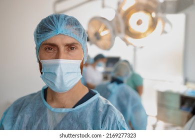 Close up of doctor in mask standing in operating room before surgery on background of colleagues - Powered by Shutterstock