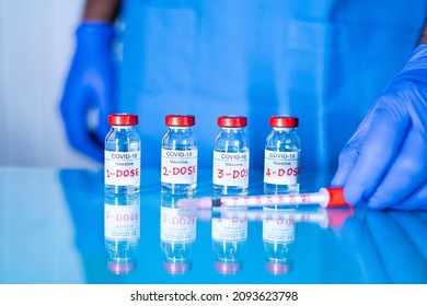 Close up of doctor placing multiple doses of covid-19 or coronavirus vaccine and syringe on table for vaccination to protect againt coronavirus variants or to stop pandemic - Shutterstock ID 2093623798