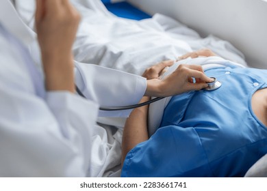 Close up of doctor sitting on bedside of male patient in hospital - Shutterstock ID 2283661741