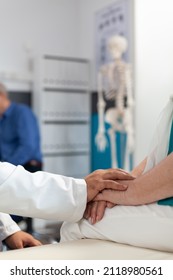 Close Up Of Doctor Supporting Retired Woman With Physical Pain, Holding Hands Of Patient To Assure Recovery And Remedy. Medic Comforting Aged Person With Arthritis At Physiotherapy