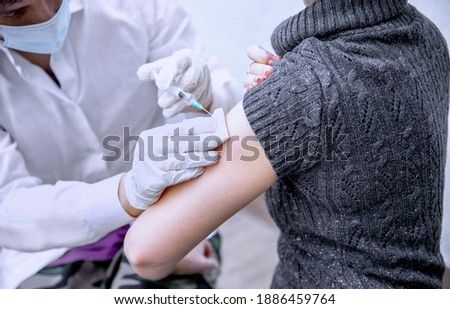 Close up Doctor with syringe and cotton to make injection to patient with protective medical mask. Covid-19 (Corona virus) vaccine. Immunization and prevention concept