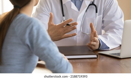 Close up doctor therapist consulting female patient at meeting, sitting at work table with laptop, physician gp explaining, giving recommendation at medical appointment, healthcare insurance concept