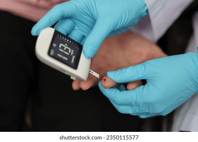 close up doctor using glucometer checking blood sugar level of senior woman. check diabetes concept