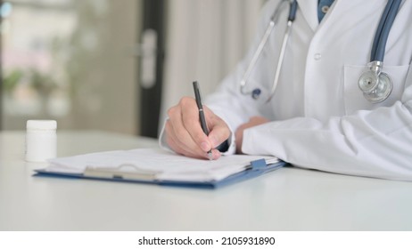 Close Up Of Doctor Writing Report On Paper