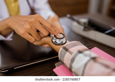 Close Up Of Doctor's Hand With Stethoscope Checking Heart Rate On Patient's Wrist