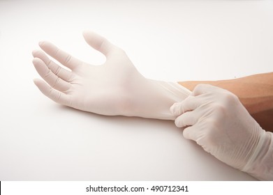 Close Up Of Doctors Hands Putting On Nitrile Gloves Isolated Over White