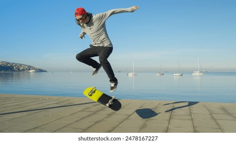 CLOSE UP DOF Unrecognizable skateboarder skateboarding, jumping ollie flip trick on promenade along the coast on sunny day. Skateboarder jumping kickflip trick with skateboard on the beach - Powered by Shutterstock