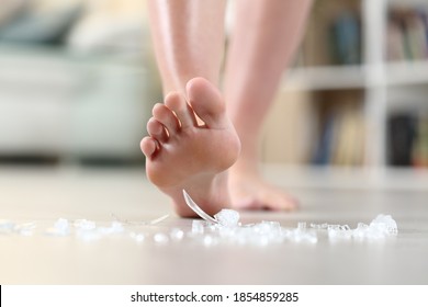 Close Up Of A Domestic Accident Of Woman Bare Foot Stepping On Broken Glass On The Floor At Home